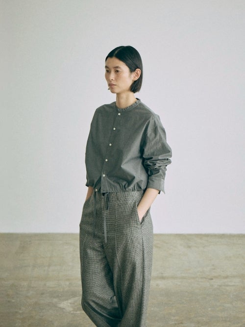 nicholson&nicholson（ニコルソンアンドニコルソン）のグレー系ショート丈フリルカラーシャツを着用した女性モデルの斜め前からのスタイリング画像です